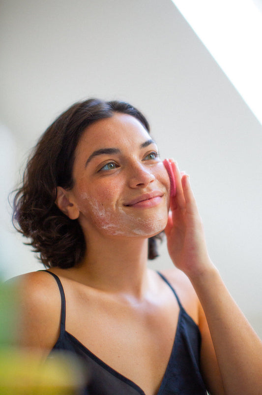 A woman using Boie's facial scrubber to exfoliate